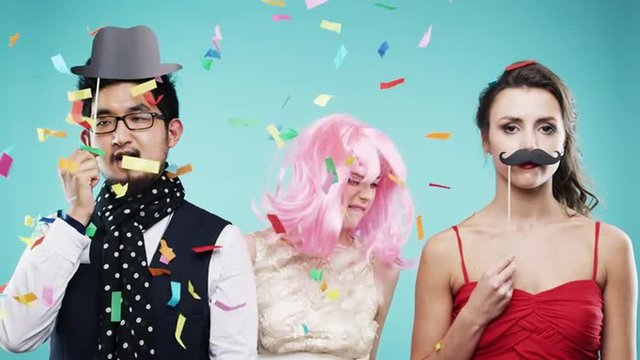 Three attractive friends dancing at party confetti shower slow motion photo booth 