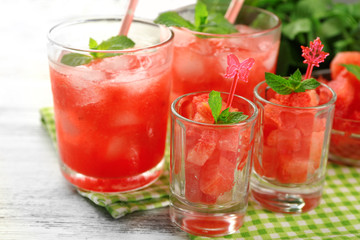 Cold watermelon desserts and drinks in glasses, on wooden table background