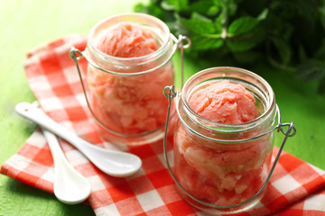 Watermelon ice cream in glass jars  on color wooden background