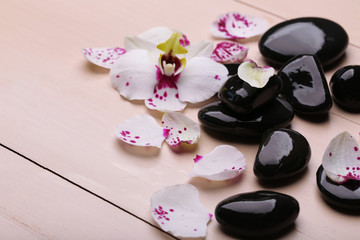 Orchid and zen stones on wooden background close-up