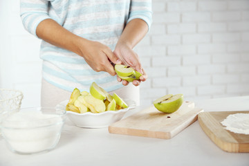 Female hands slicing apple for pie, close-up, on light background