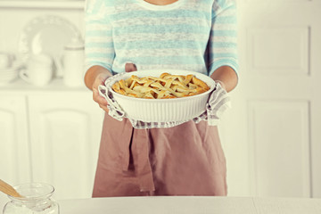 Homemade apple pie  in female hands, on light background