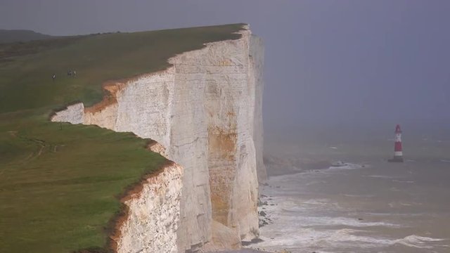 A beautiful establishing shot of the white cliffs of Dover at beachy head, England with lighthouse. 