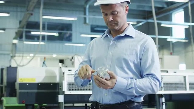 Engineer in Hard Hat Measuring Detail on Factory