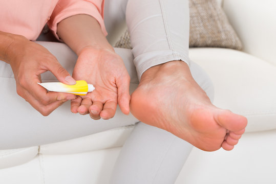 Woman's Hand Applying Cream On Foot