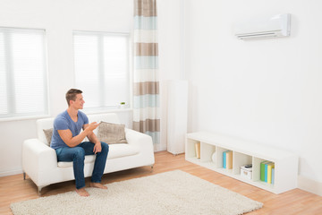 Young Man Operating Air Conditioner