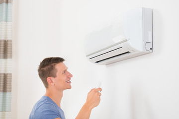 Man With Remote Control To Operate Air Conditioner