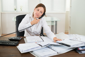 Businesswoman Using Telephone While Doing Accounting