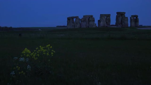 Stonehenge in the distance on the plains of England at night.