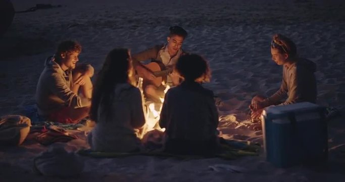 Beach Party at sunset with bonfire and roasting marshmellows with friends