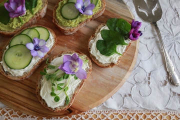 Fototapeta na wymiar Green sourdough open face sandwiches with purple edible flowers