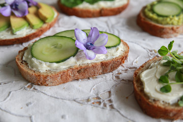 Green sourdough open face sandwiches with purple edible flowers