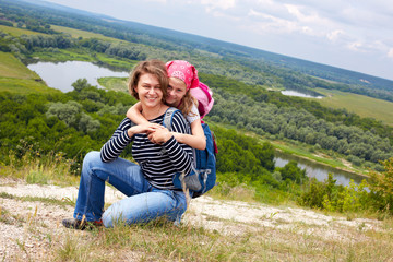 Adult and child standing on a mountaintop near  river.  