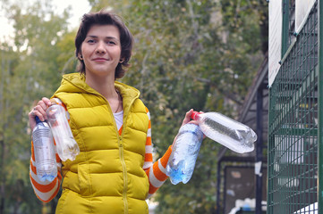 Woman throws plastic bottles to recycling container