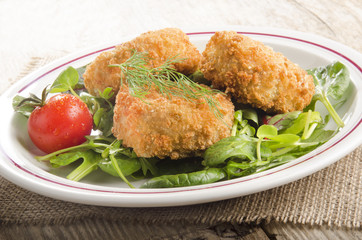 warm fish cake with tomato on green salad