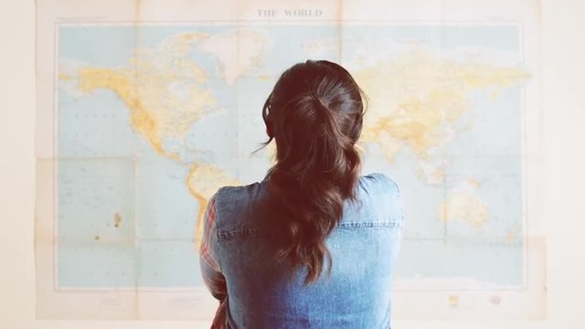 Tourist woman looking at world map planning travel adventure