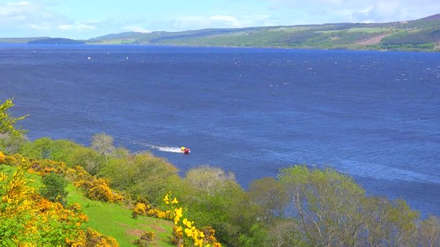 An establishing shot of Loch Ness, Scotland with speedboat passing.
