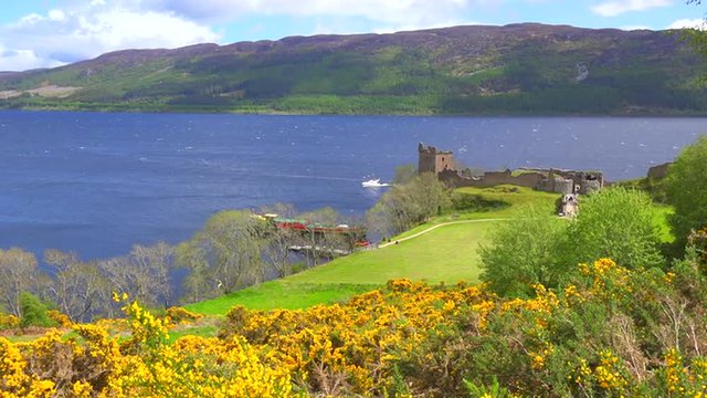 An establishing shot of Loch Ness castle, Scotland with speedboat passing.