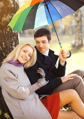 Happy young couple together with colorful umbrella in the park