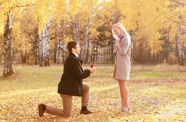 Kneeled man proposing ring to a woman in autumn park © rohappy