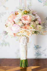 
Elegant bridal bouquet of roses in light colors standing on the table.