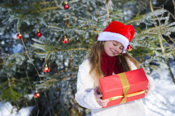 Funny  little girl with christmas gift in the winter forest