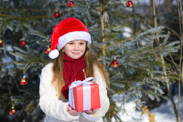 Smiling  little girl with christmas gift in the winter forest