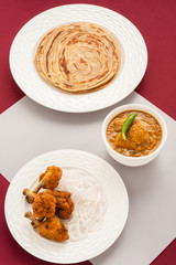 Fried chicken and curry with parotta - Overhead view of deep fried spicy chicken lollipops served with Indian chicken curry and wheat parotta (Indian bread) as a meal. Natural light used.