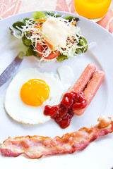 fried eggs with bacon, sausages and toasts on white plate