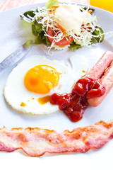fried eggs with bacon, sausages and toasts on white plate