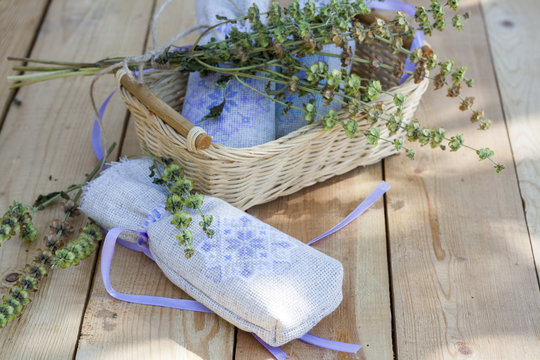 Sachet with ukrainian embroidery, sheaf of wheat and dried herbs on wooden background