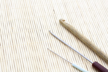 Crochet hooks on light makisu close-up, selective focus