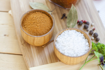 Spices: salt and pepper in wooden pot with tomatoes and herbs close-up, selective focus