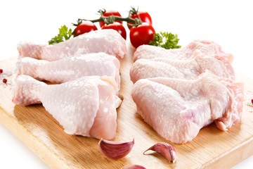 Raw chicken wings and drumsticks on cutting board on white background 