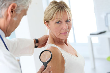 Elderly woman consulting doctor for skin control