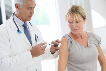 Doctor injecting flu vaccine to patient's arm