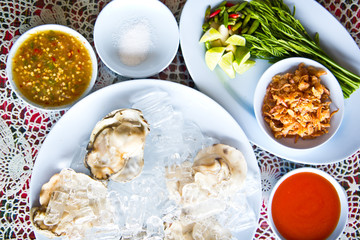 Oysters on ice serving with vegetables in Thai seafood restaurant