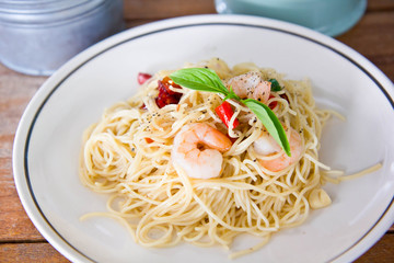Chilli prawn spaghetti on wooden table in restaurant