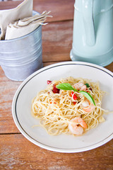 Chilli prawn spaghetti on wooden table in restaurant