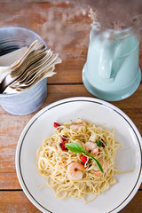 Chilli prawn spaghetti on wooden table in restaurant