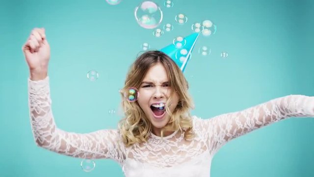 Crazy face woman dancing in bubble shower slow motion photo booth blue background