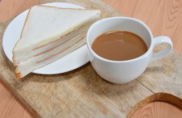 bologna sandwich and coffee on wooden chop block