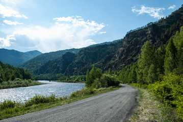 Asphalt road on the background of the Sayan mountains on a summer day. Russia, Siberia. Highway M-54.