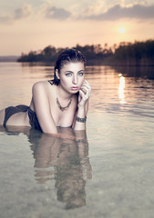 Beautiful Young Woman Wearing a Bikini in Water at Sunset
