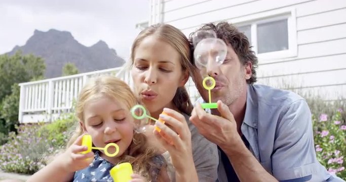Happy family blowing bubbles in the yard at home