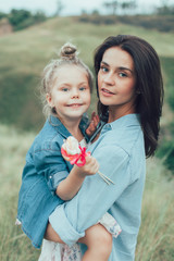 The young mother and daughter on green grass background 