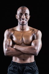 Fototapeta na wymiar Portrait of happy shirtless athlete standing with arms crossed
