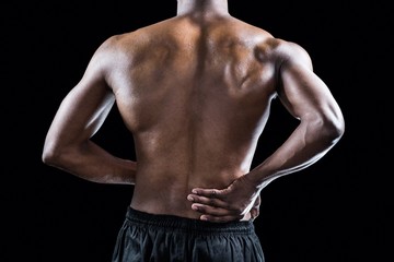Fototapeta na wymiar Mid section of muscular athlete suffering through back pain