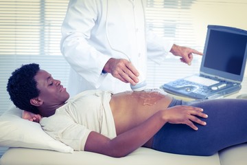 Obraz na płótnie Canvas Doctor applying ultrasound gel on belly of woman