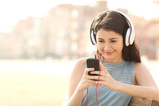Girl listening music with headphones from a smart phone